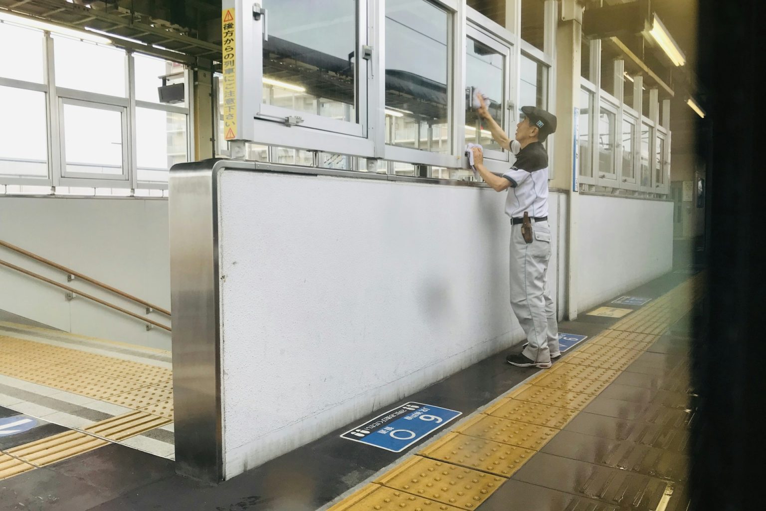 駅のホームで、制服姿の男性が窓ガラスを拭いている