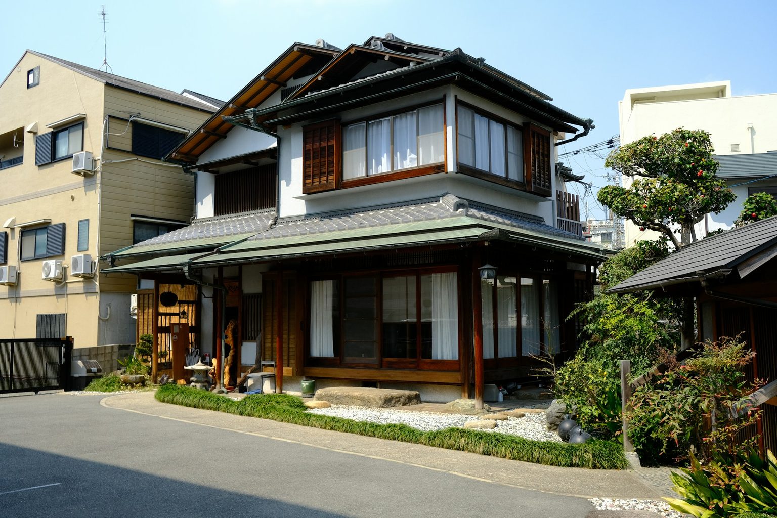 瓦屋根の木造の家と、手入れされた庭木