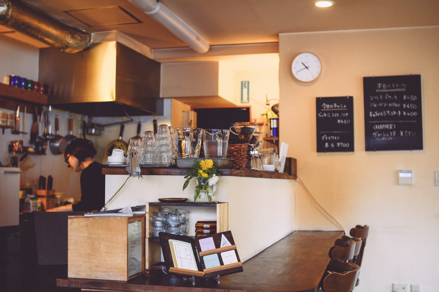 黒板のメニューが掛かった、明るい喫茶店のカウンターと厨房
