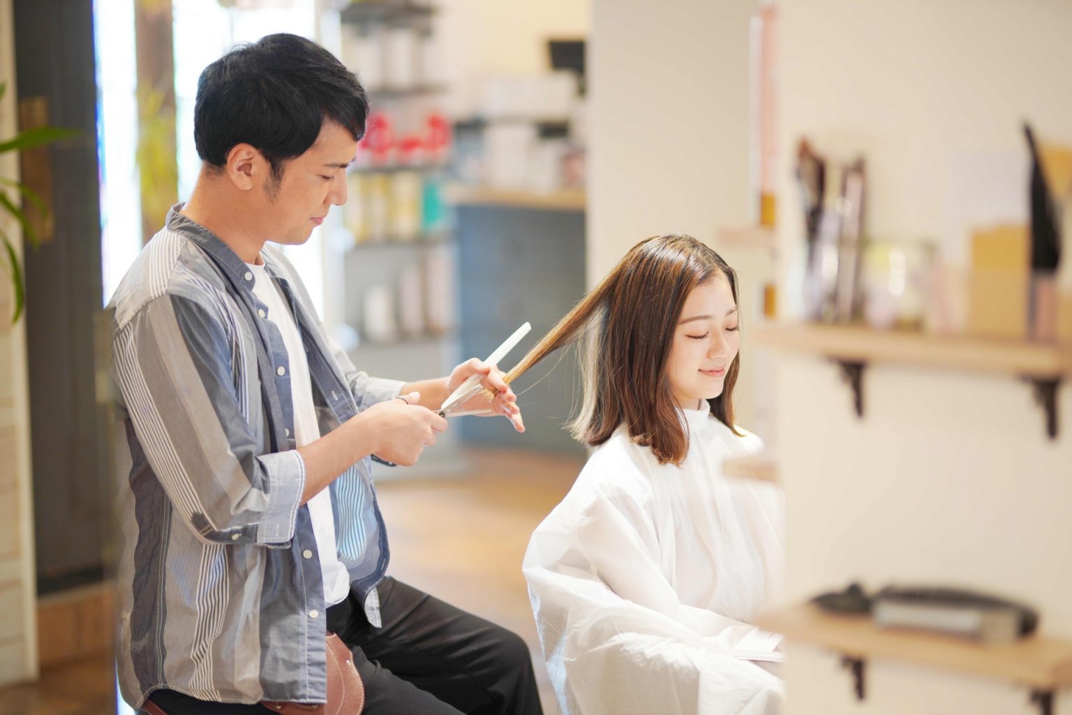 女性の髪を整えるスタイリスト