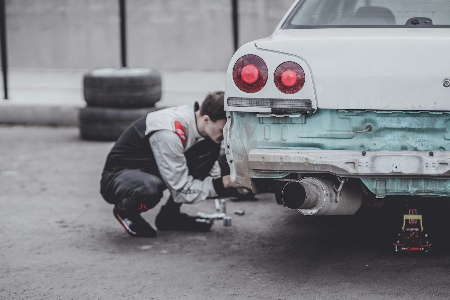 しゃがんで車の足まわりを確かめる整備士