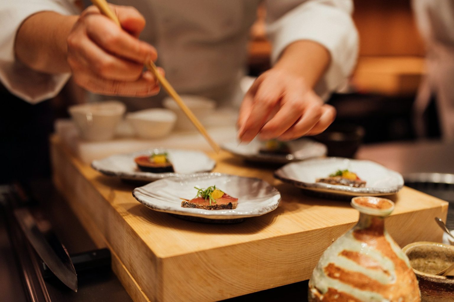 木の台で料理を盛りつける料理人の手元