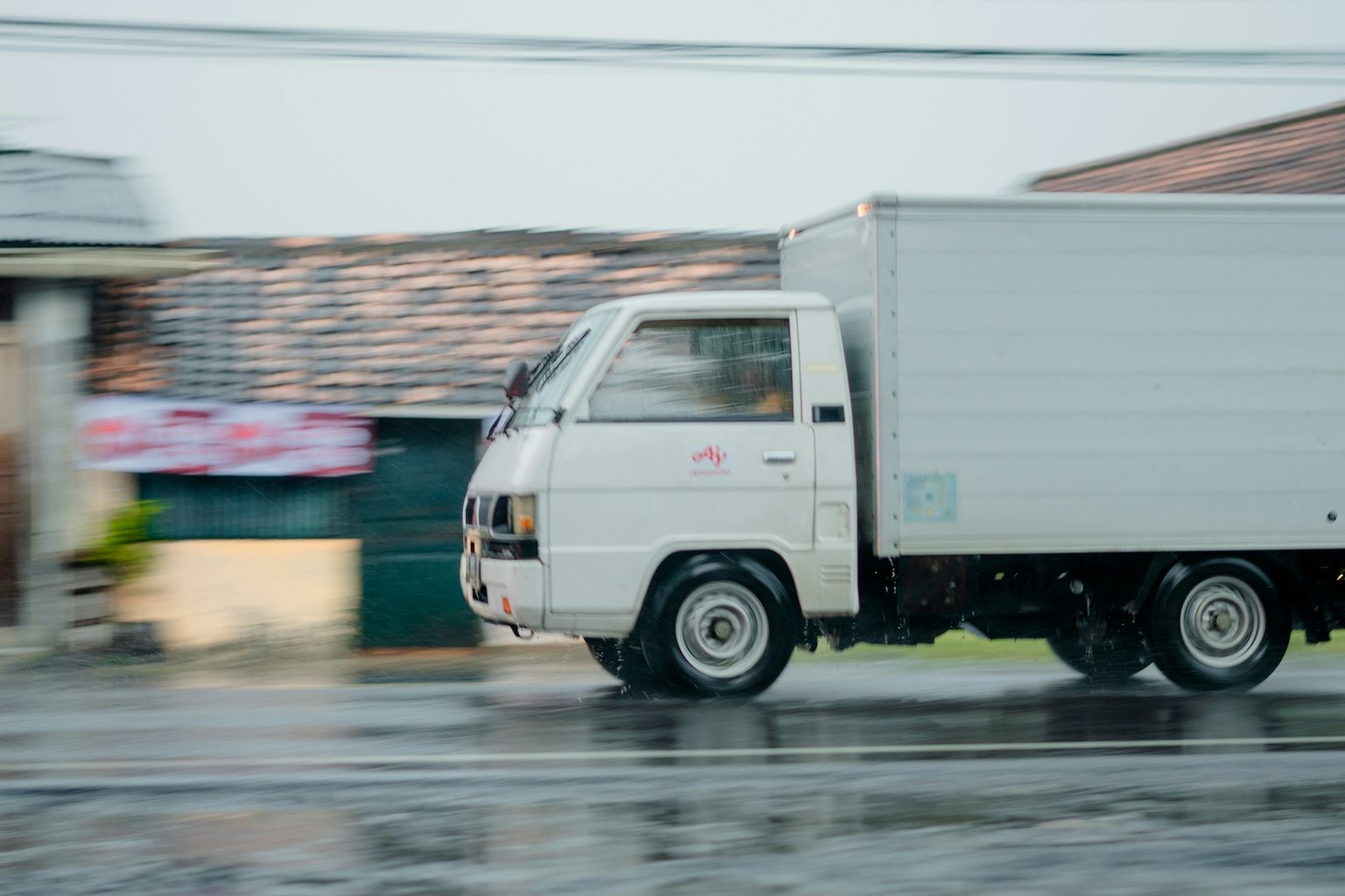 雨の道路を走る白いトラック